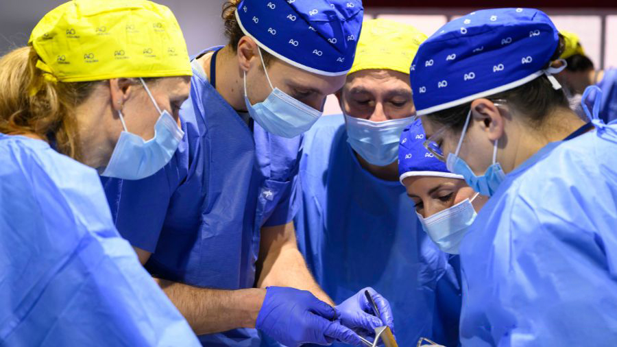 A group of surgeons at work in their blue scrubs and face masks.