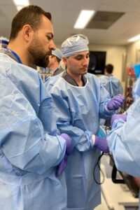 Two surgeons at work in blue scrubs and gloves.