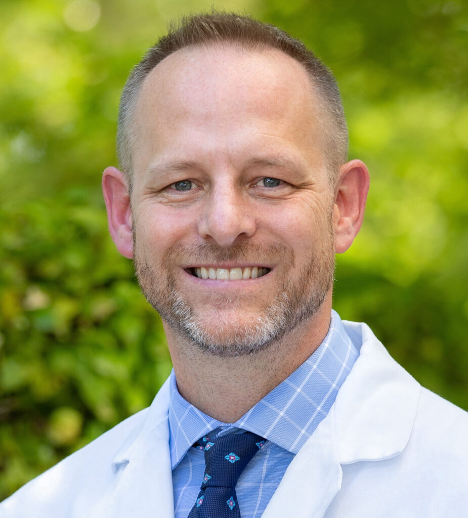 Headshot photo of Dr. Travis Tollefson headshot wearing a white coat while smiling